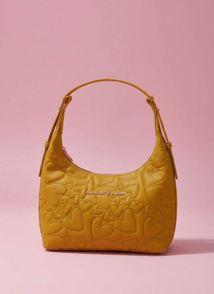 Bolso mostaza con bordado decorativo y cierre de cremallera. Bolso hobo Agatha Ruiz de la Prada con bordado de corazones.