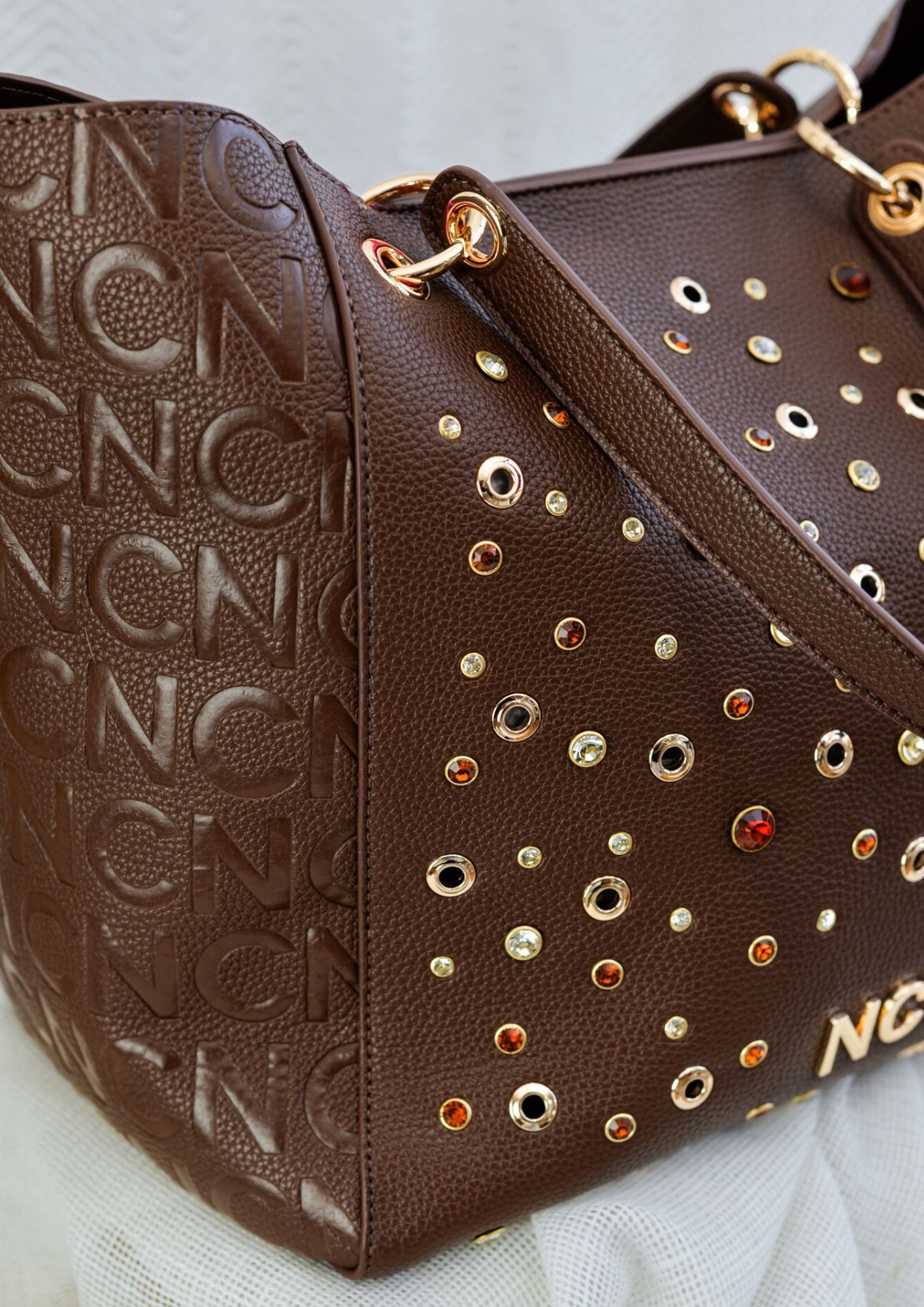 Detalles bolso tote pedreria chocolate Vista lateral de bolso tote con textura granulada