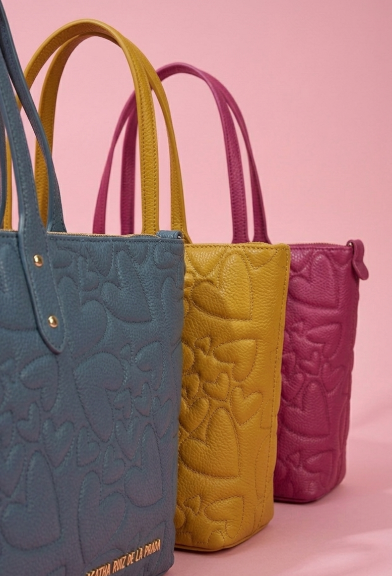 Bolso shopper de gran capacidad confeccionado en piel vegana. Detalle del logo metálico dorado del bolso shopper.
