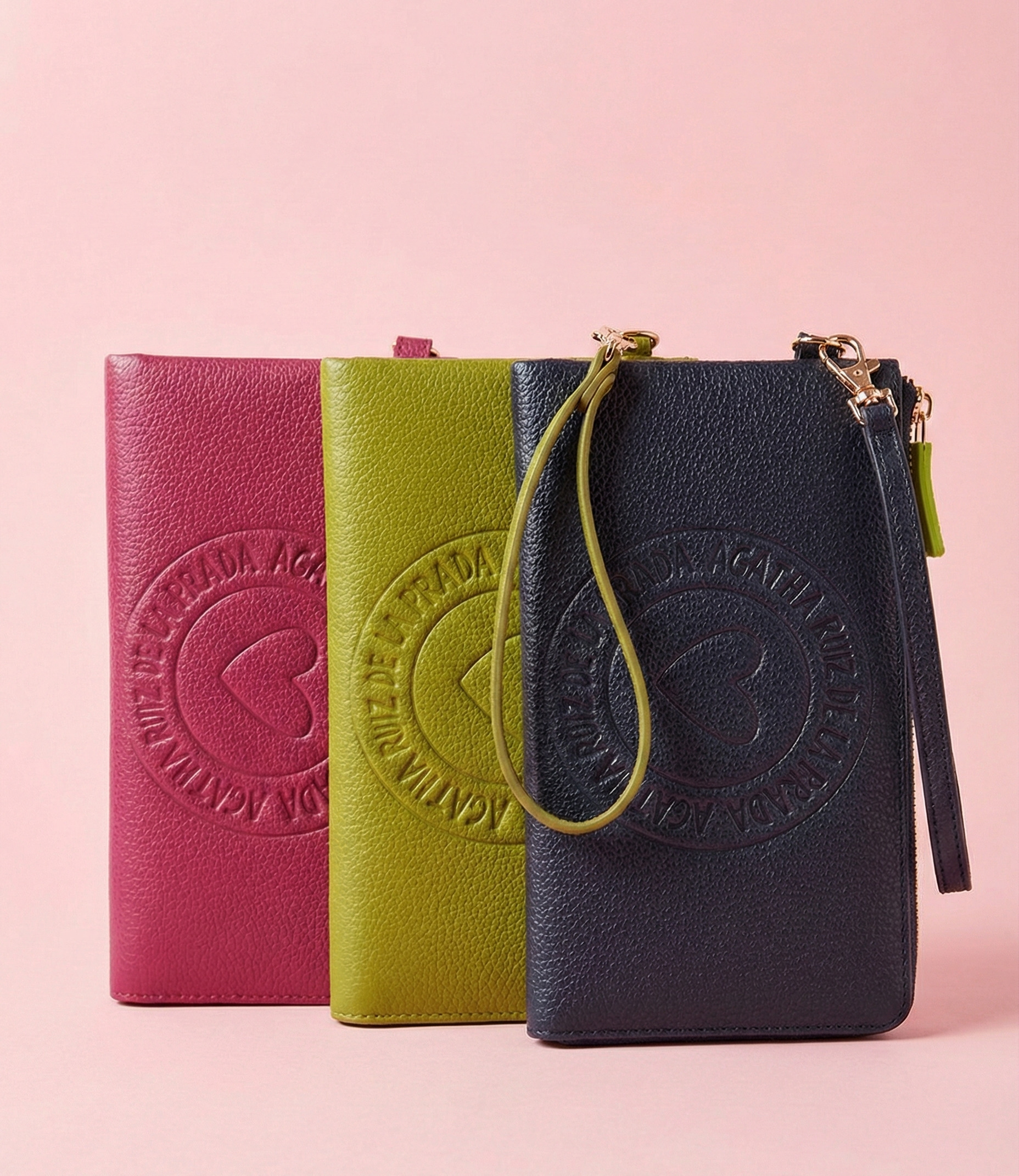 Cartera de mano Agatha Ruiz de la Prada de piel sintética lisa. Cartera Agatha Ruiz de la Prada disponible en azul marino, verde oliva, y fucsia.