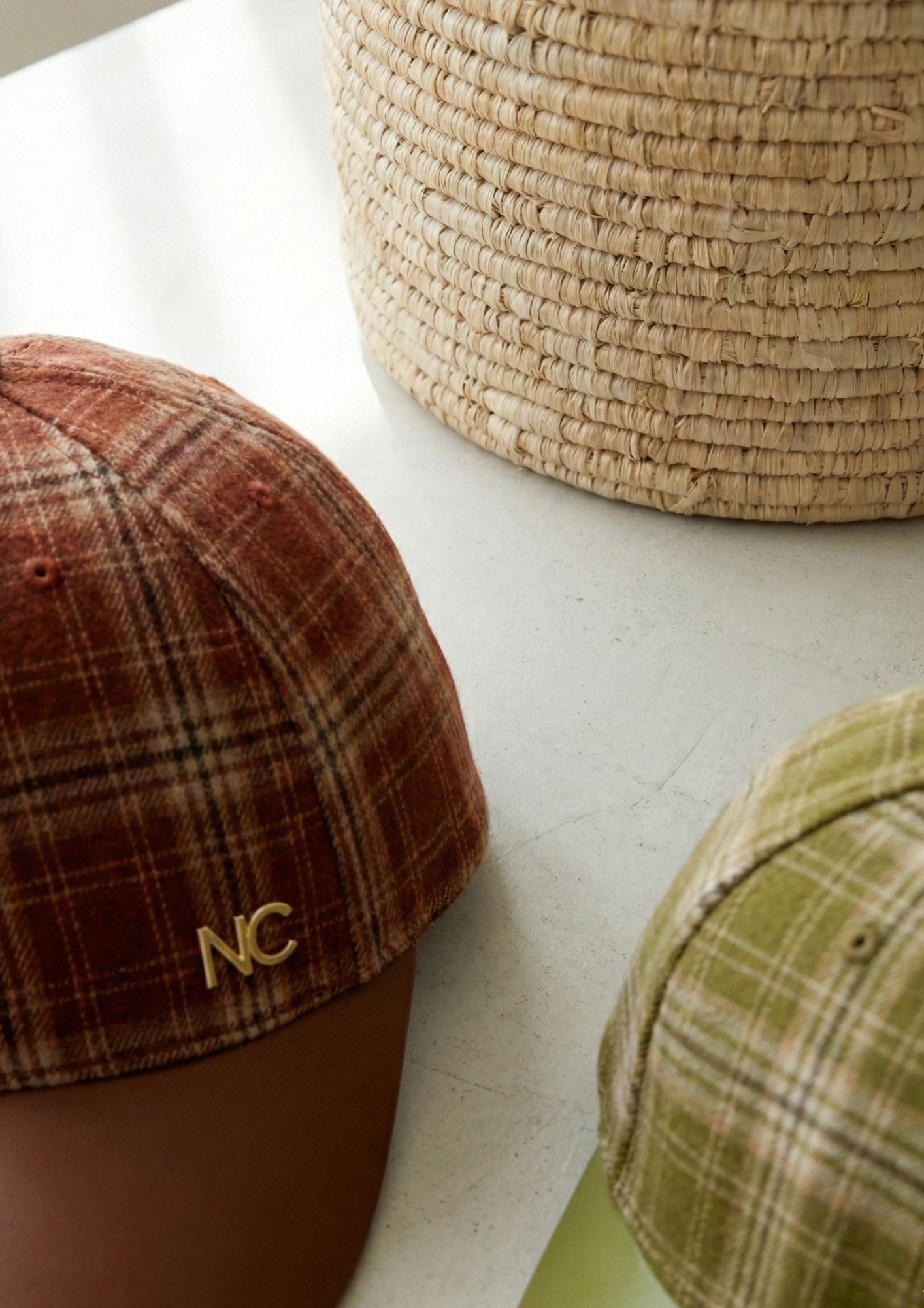 Detalle del logo NC en metal sobre gorra de cuadros Vista frontal de gorra de cuadros con detalle metálico